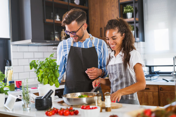 快乐的多民族夫妇准备自制的番茄和罗勒意大利面。在家做饭图片下载