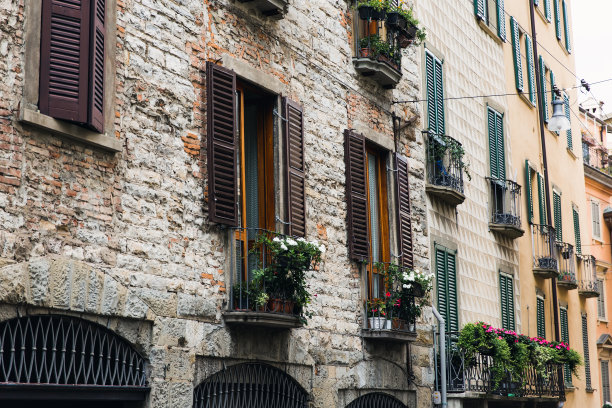 在欧洲的城市里，一幢窗户上装饰着鲜花的老房子的正面。图片下载
