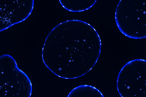 透明深蓝滴胶与浅蓝色霓虹灯形成背景或图案。凝胶滴在深蓝色的背景，病毒防护或化妆品概念。图片下载