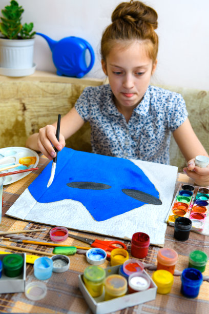 一个画着蓝色水粉纸板的女孩，在家里进行艺术创作，制作有创意的艺术品图片下载