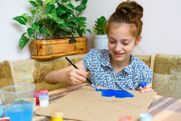 一个画着蓝色水粉纸板的女孩，在家里进行艺术创作，制作有创意的艺术品图片下载