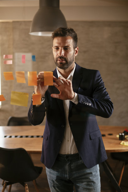 会议室的商人在玻璃墙上使用便利贴。图片下载