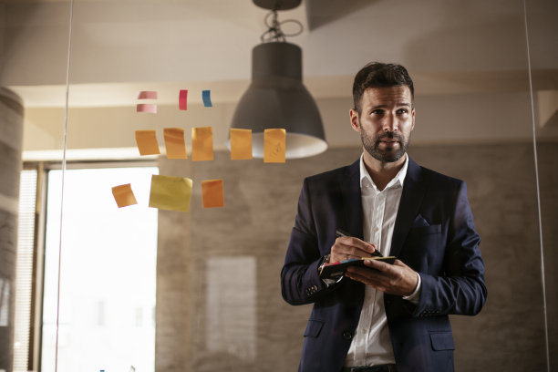 会议室的商人在玻璃墙上使用便利贴。图片下载