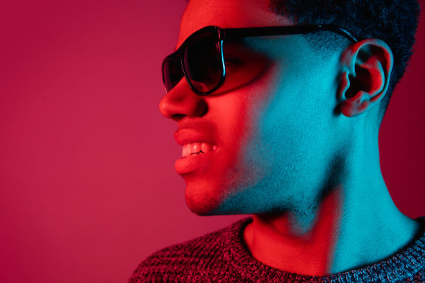 非裔美国人的肖像被隔离在彩色霓虹灯下的红色工作室背景上图片下载