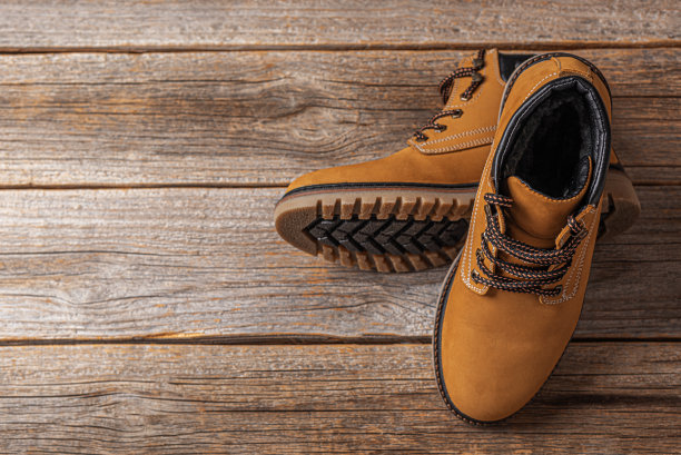 木制背景上的黄色冬季靴子图片下载