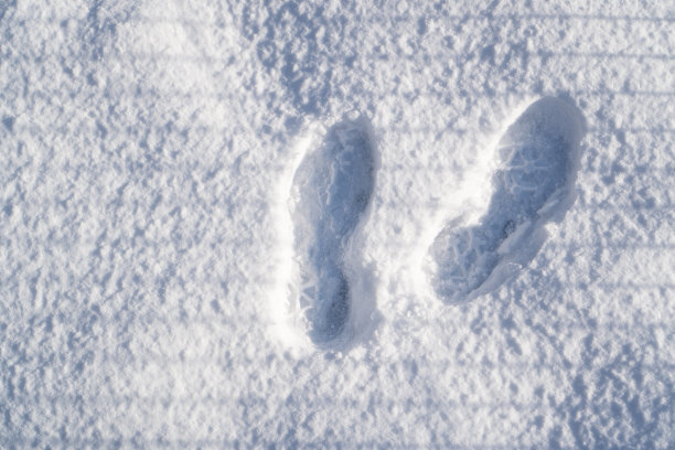 雪地鞋印俯视图。白雪上的脚印。雪中前进的近距离脚步声图片下载
