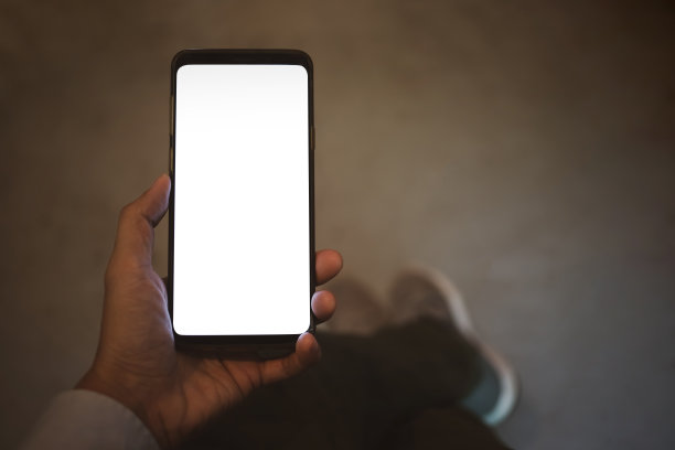 近手握智能手机空白白屏幕样机。俯视图图片下载