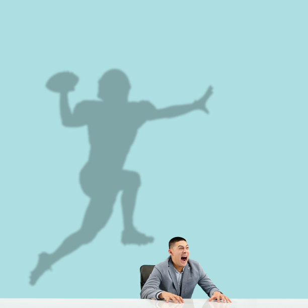 一个年轻人在办公室工作期间梦想着在大型体育运动中的未来。成为一个传奇。梦的影子在他身后的墙上。Copyspace。图片下载