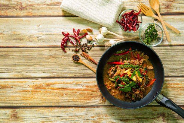 厨师用手在平底锅里翻炒馅肉馅饼，摆在木桌上以各种食材为背景。烹饪过程的概念。准备美食的后台。从以上观点。图片下载