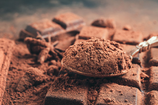 棕色可可粉在勺子上的巧克力棒，切碎的巧克力方块在黑色的背景图片下载