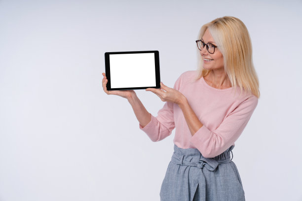 一个欧洲妇女的肖像使用平板电脑在休闲服装孤立在灰色背景图片下载