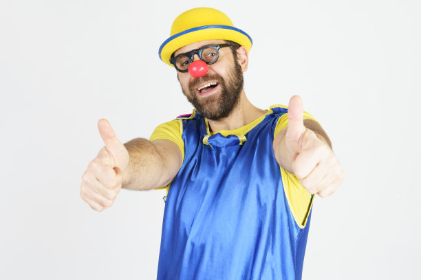 一个小丑穿着亮蓝色和黄色的衣服，戴着眼镜和帽子，显示了一个OK的手势图片下载