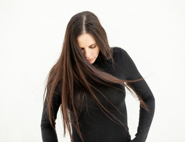 美丽的成年女人与长头发在风中白色的背景图片下载