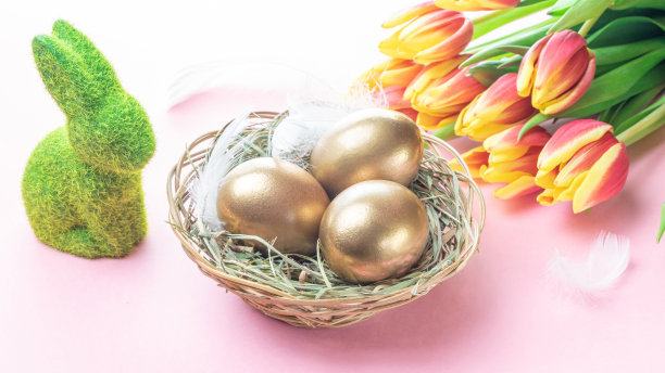 复活节彩蛋篮子与春天的郁金香，白色羽毛在柔和的粉红色背景在快乐复活节装饰。春天节日的概念。图片下载