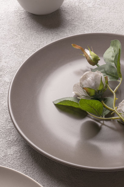 玫瑰色盘在桌上，灰色柔和的色彩。浪漫简约的生活方式静物。垂直照片为一个爱情故事图片下载