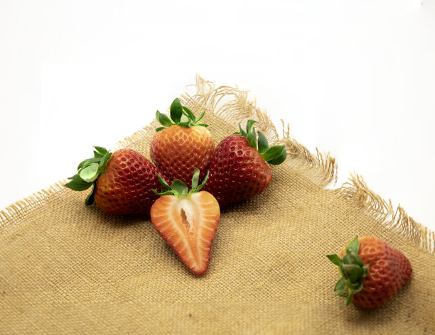 白色背景上棕色麻袋布上的草莓。图片下载