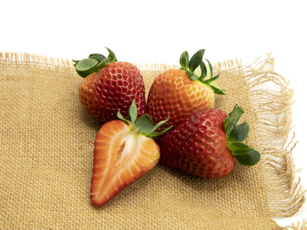 白色背景上棕色麻袋布上的草莓。图片下载