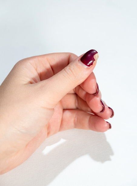 拇指上的指甲油涂层破损破损。特写镜头。白色背景。图片下载