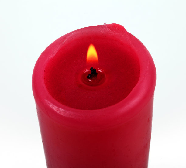 白色背景上燃烧的红色蜡烛，孤立，特写。图片下载