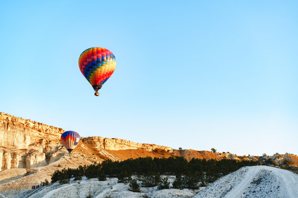 彩色的气球在晴朗的天空中飞行在巨大的白色的山图片下载