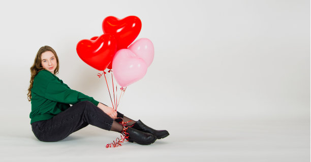 横幅。女孩手里拿着气球，坐在白色的背景上。情人节的概念图片下载