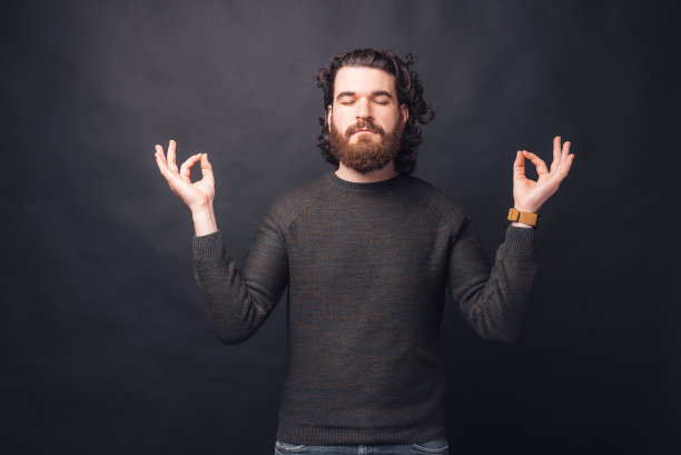 照片英俊的男子与胡子在禅宗姿态在黑色的背景图片下载