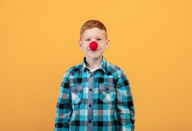 黄色背景上有小丑鼻子的小男孩素材图片