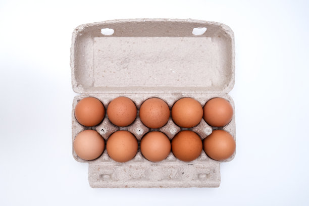 棕色的鸡蛋装在可回收的纸盒内，放在白色的桌子上图片下载