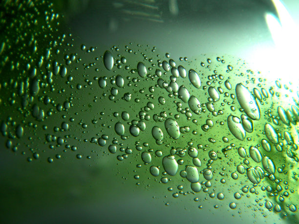 绿色的油滴在水中。不同大小的气泡在绿色抽象背景上图片下载