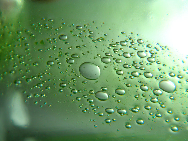 绿色的油滴在水中。不同大小的气泡在绿色抽象背景上图片下载