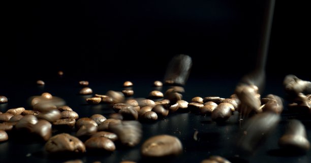 烘焙过的咖啡豆落在黑色的表面。图片下载