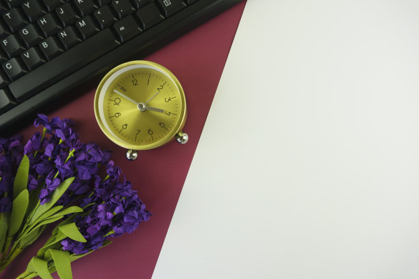 桌子时钟，花和电脑键盘在多色的背景。图片下载