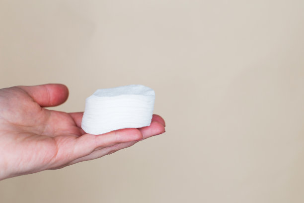 一个女人的手拿着棉签在米色的背景图片下载