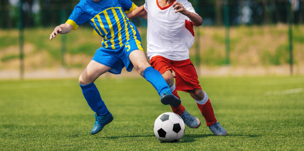 两个足球男孩在对队踢球。青年足球运动员在决斗中奔跑和踢足球比赛。青少年运动员体育比赛。学校培训背景图片下载
