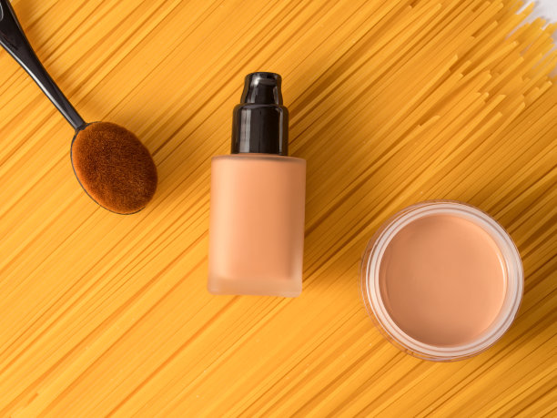 粉底霜和液体粉底用化妆刷涂在黄色背景上图片下载