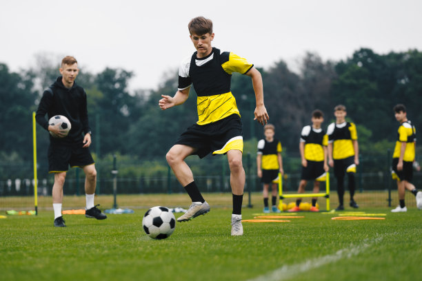 年轻足球运动员在训练课程。青年队队员赛前踢球练习单元。足球男孩与年轻教练图片下载