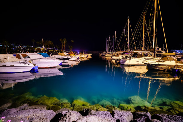 夜晚的照片码头与系泊的船只和透明的蓝色水显示岩石底部。大加那利岛。图片下载
