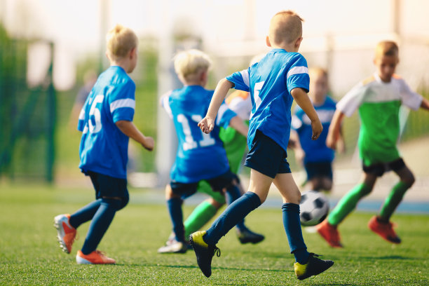 男孩们在学校操场上踢足球。匿名的年轻运动员在一个夏天踢足球图片下载