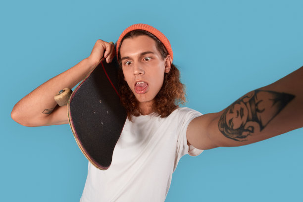 年轻的成年人拿着滑板做傻傻的自画像图片下载