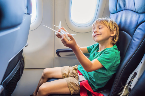 小男孩在度假的商用飞机上玩玩具飞机图片下载