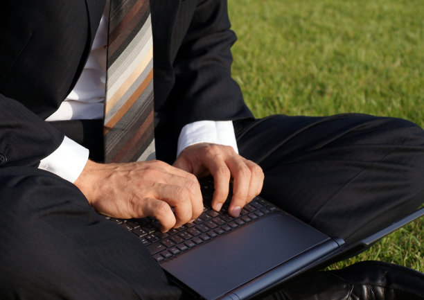 一个商人坐在公园外面，用他的笔记本电脑工作图片下载