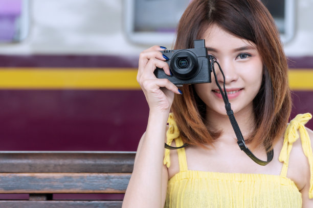 摄影师年轻女子拿着数码相机在车站拍照。迷人的女孩旅行与她的相机在火车站。图片下载