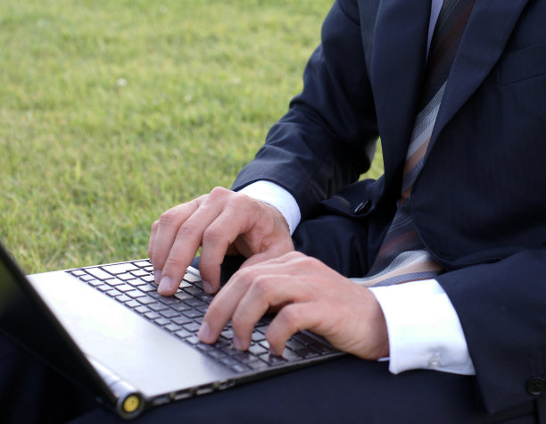 一个商人坐在公园外面，用他的笔记本电脑工作图片下载