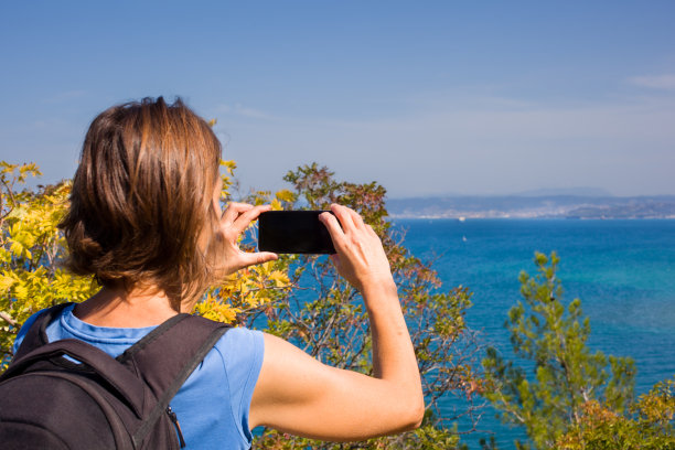 一位女徒步旅行者和一个背包客用她的智能手机拍下了大海的照片图片下载
