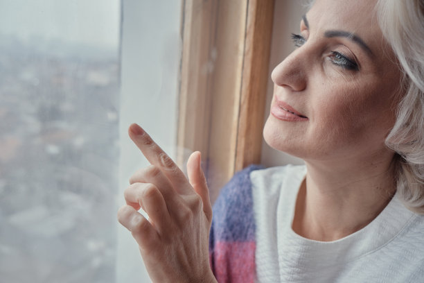 沉思的成熟女人喝茶看窗外，封闭和隔离的概念，选择性的焦点图片下载