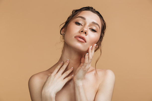 温柔的女人站在赤裸的孤立看着相机。图片下载