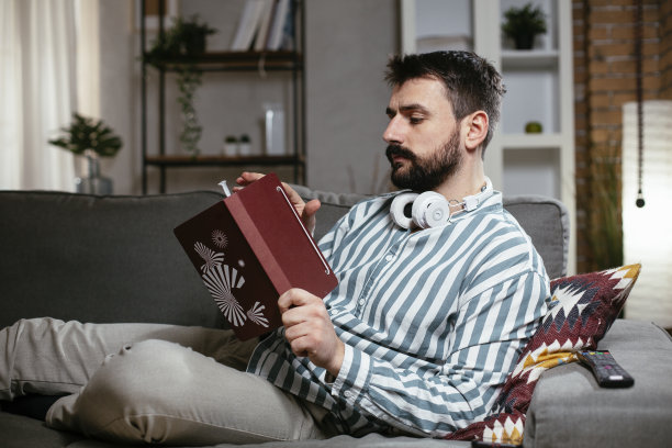 一个年轻人正在沙发上看书图片下载
