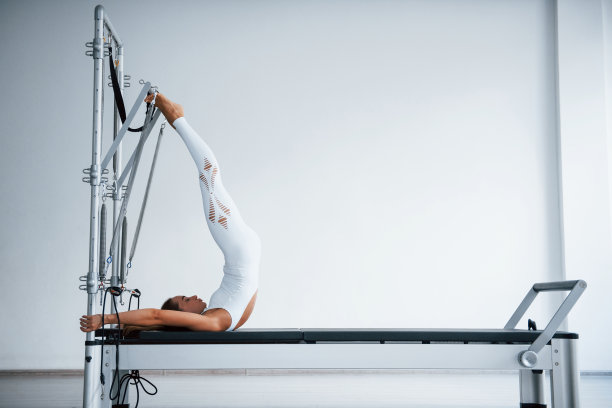 有效的机器。身材苗条、自信的年轻运动女性在健身中心使用特殊设备进行锻炼图片下载