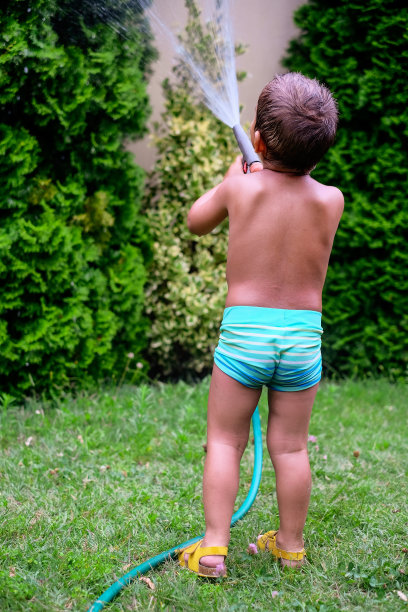 蹒跚学步的小男孩在花园里洗澡图片下载