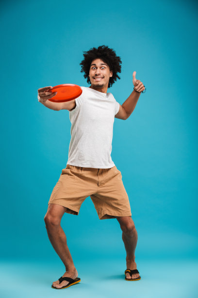 英俊开朗的年轻非洲卷发男人拿着沙滩玩具竖起大拇指。图片下载